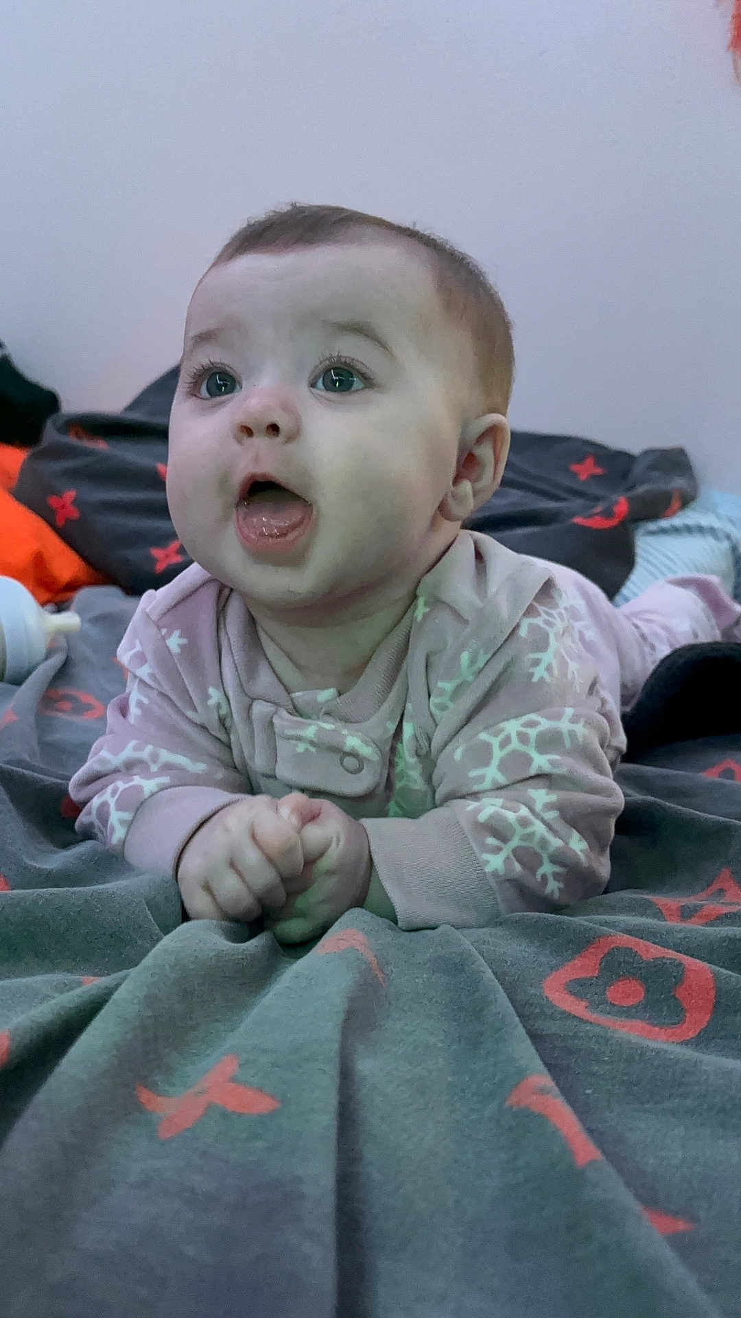 Maeve joined the competition — help win amazing prizes! baby, infant, child, blanket, patterned_blanket, pink_outfit, hands, face, mouth_open, eyes, indoor, soft_lighting, lying_down, cute, expression, clothing, bedroom, cozy, toddler, person