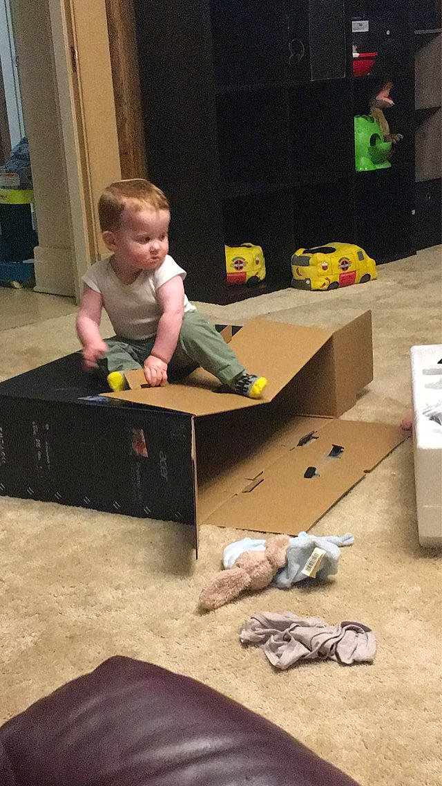 Nicholas is registered to the contest to win money with this photo: ankle, baby, baby_toddler_clothing, baby_toys, balance, barefoot, box, cardboard, carton, child, foot, outdoor_shoe, packaging_and_labeling, person, play, shipping_box, toddler, toy