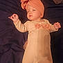 baby, infant, child, headwrap, bow, onesie, floral, pink, peach, blanket, laying_down, sleepy, cute, soft_lighting, portrait, indoor, young_child, clothing, face, hand