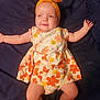 Addalyn is registered to the contest to win money with this photo: baby, infant, headband, yellow, floral_dress, smile, face, arms_outstretched, lying_down, fabric_background, cute, happy, child, skin, legs, barefoot, playful, indoors, portrait, one_person