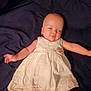 baby, infant, white_dress, sleepy, lying_down, blanket, indoor, child, cute, soft_lighting, portrait, toddler, wearing_clothes, peaceful, small_hands, head, skin, face, arms, legs