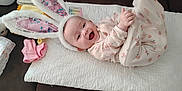 Kaiya is registered to the contest to win money with this photo: baby, baby_girl, blanket, bunny_ears, cheerful, child, clothing, couch, cute, happy, headwear, indoor, infant, lying_down, onesie, person, pink, portrait, smile, soft_toys