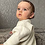 baby, child, face, eyes, sweater, cream_color, curly_hair, indoor, couch, plush, texture, portrait, looking_up, skin, person, soft_lighting, cute, young, infant, sitting
