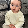 toddler, child, baby, indoor, carpet, sweater, cream, pants, sitting, curious, face, hands, couch, furniture, hair, long_eyelashes, cozy, portrait, young, cute