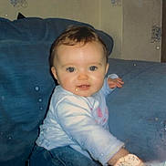 Taylor is registered to the contest to win money with this photo: baby, child, blue_couch, indoor, smile, face, person, clothing, jeans, long_sleeve, young_child, cute, sitting, home, furniture, portrait, infant, happy, reaching, photograph