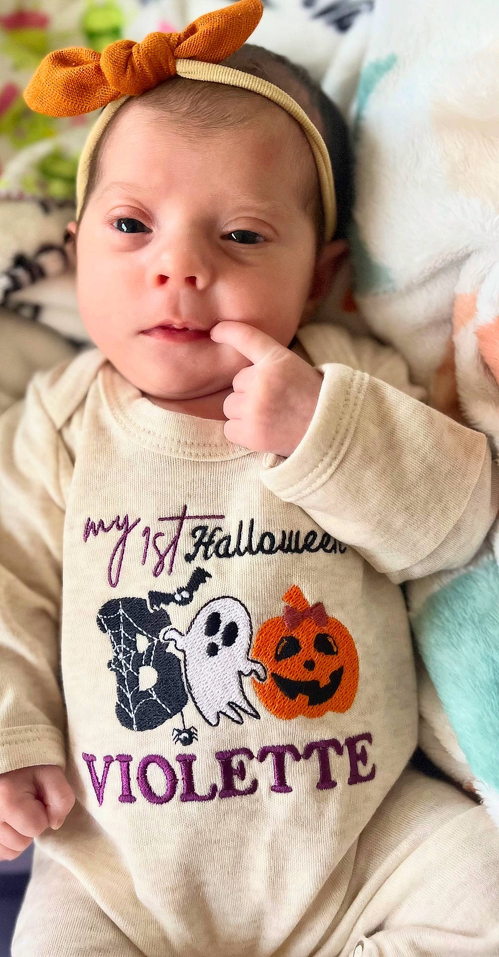 Violette is registered to the contest to win money with this photo: baby, blanket, child, clothing, cute, embroidery, face, ghost, halloween, hand, headband, indoors, infant, newborn, onesie, orange_bow, portrait, pumpkin, sleepwear, soft