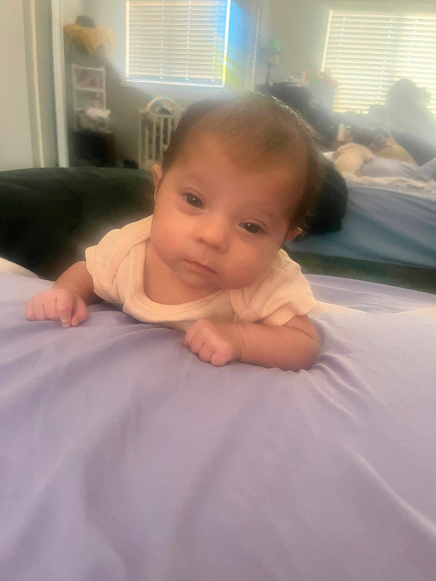 Violette is registered to the contest to win money with this photo: baby, infant, blanket, bedroom, soft_light, face, person, sleepy, hands, curious, indoors, toddler, lying_down, young_child, head, skin, clothing, window, home, cozy