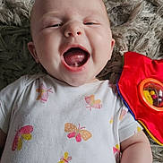 Ruby joined the competition — help win amazing prizes! baby, smiling, infant, onesie, butterfly_pattern, toy, red, green, yellow, floor_rug, happy, cute, child, playtime, closeup, skin, hand, mouth_open, face, lying_down