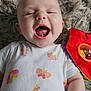 baby, smiling, infant, onesie, butterfly_pattern, toy, red, green, yellow, floor_rug, happy, cute, child, playtime, closeup, skin, hand, mouth_open, face, lying_down