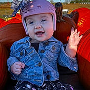 Raven joined the competition — help win amazing prizes! baby, child, smiling, waving, helmet, pink_helmet, denim_jacket, jacket, pumpkin_patch, pumpkins, outdoor, autumn, fall, blue_sky, portrait, sitting, infant, happy, patterned_pants, farm