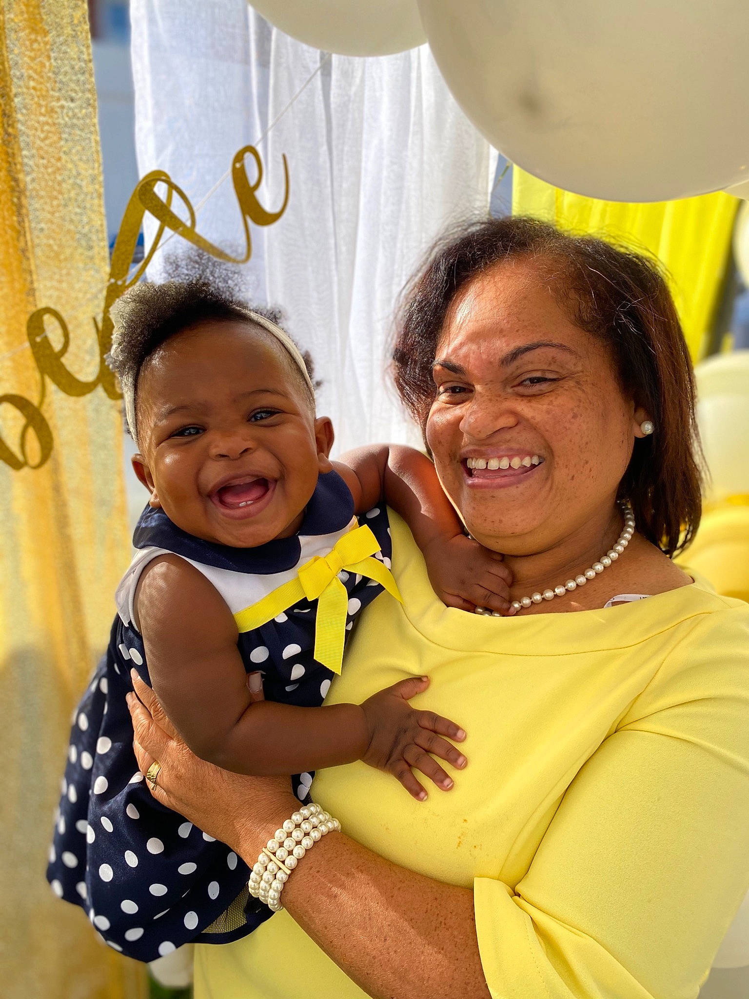 Jolie is registered to the contest to win money with this photo: baby, baby_toddler_clothing, balloon, black, child, curtain, event, fun, gesture, happy, jewellery, joy, leisure, necklace, party_supply, people, person, skin, smile, toddler