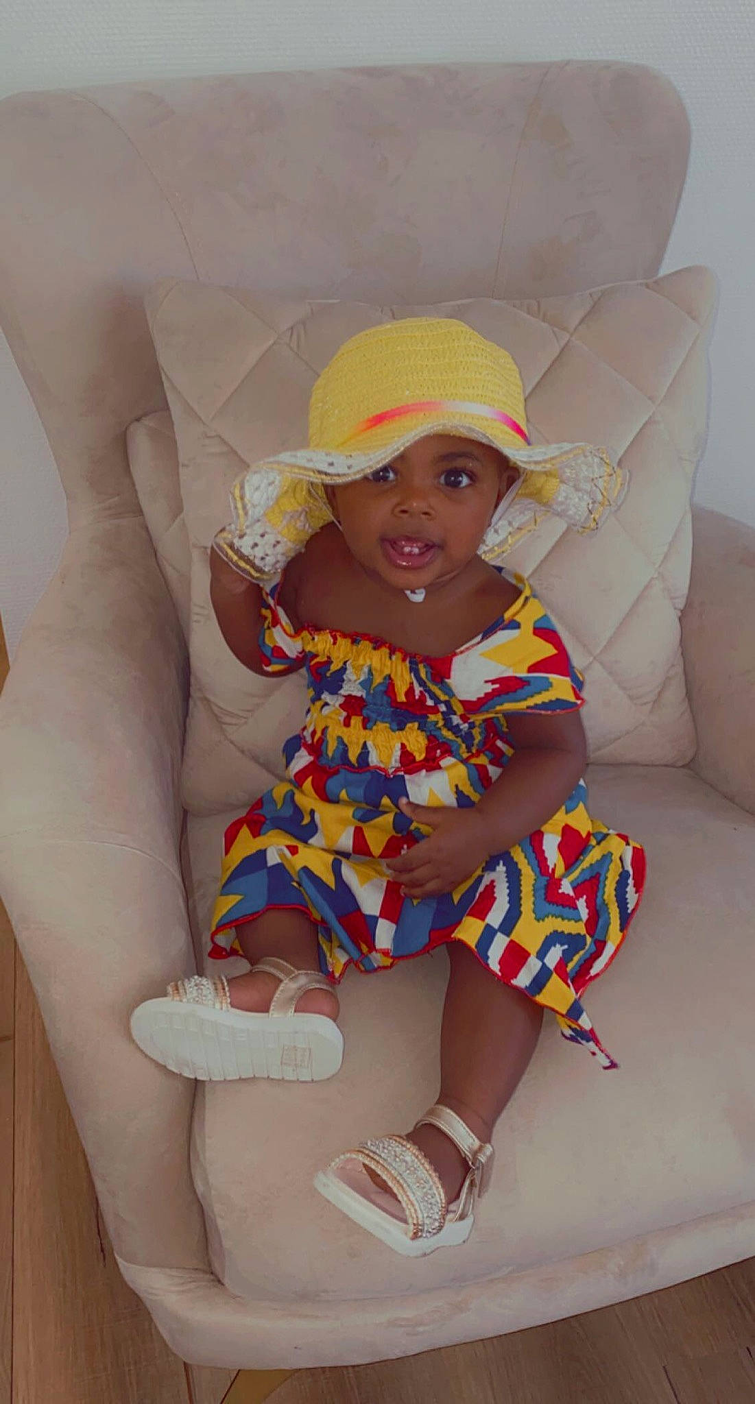 Elna participe au concours pour gagner de l'argent avec cette photo : baby_toddler_clothing, cap, child, comfort, dress, face, fun, happy, headwear, human_leg, knee, lap, leg, pattern, person, shoe, sitting, skin, sleeve, smile