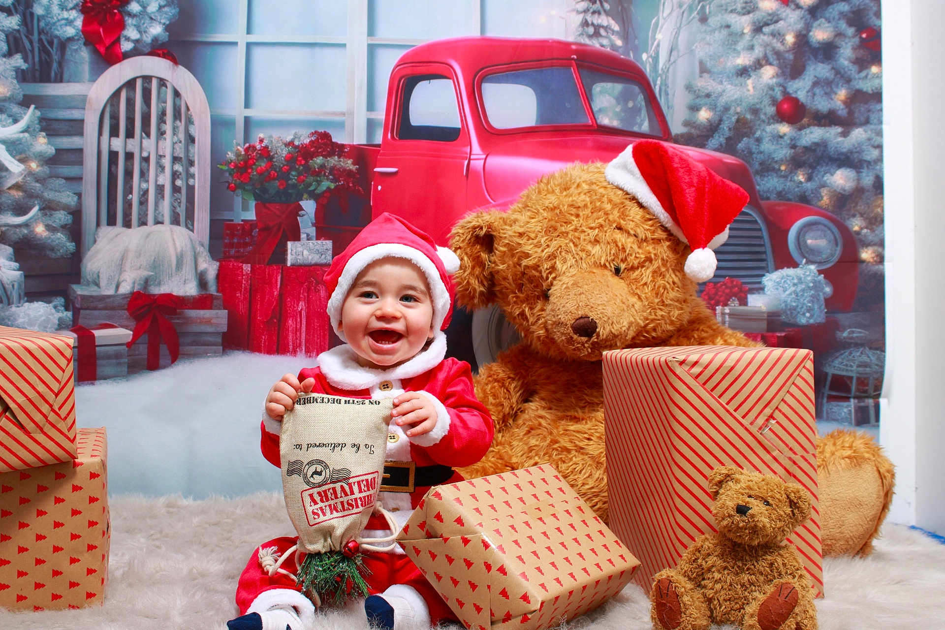 Hudson joined the competition — help win amazing prizes! baby, santa_claus, teddy_bear, christmas, gift, wrapped_gift, holiday, red_hat, smiling, toy, festive, decorations, background, car, plush_toy, floor, white_rug, child, indoor, happy
