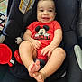 baby, car_seat, mickey_mouse, red_clothing, smiling, child, infant, toy, black_fabric, seat_belt, cute, happy, feet, hands, indoor, person, portrait, baby_toys, child_seat, infant_clothing