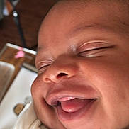 Clarence is registered to the contest to win money with this photo: baby, smiling, close_up, face, tongue_out, eyes_closed, infant, cute, happy, skin, cheeks, clothing, expression, newborn, portrait, child, indoors, joy, sleepy, wrapped