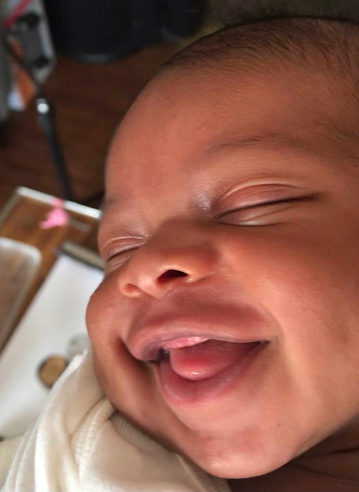Clarence is registered to the contest to win money with this photo: baby, smiling, close_up, face, tongue_out, eyes_closed, infant, cute, happy, skin, cheeks, clothing, expression, newborn, portrait, child, indoors, joy, sleepy, wrapped