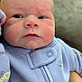 baby, infant, face, closeup, onesie, lavender, bee_pattern, hand, curious, chubby_cheeks, skin, eyes, nose, mouth, fist, blurred_background, tattoo, holding, soft_texture, portrait