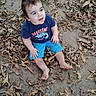 toddler, child, baby, outdoor, leaves, autumn, fallen_leaves, forest, nature, sitting, smiling, portrait, blue_shirt, blue_shorts, barefoot, dirt, ground, park, happy, daylight