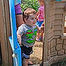 Aaron is registered to the contest to win money with this photo: child, toddler, children, playhouse, outdoor, playground, doorway, plastic, backyard, summer, sunlight, curious, standing, walking, smiling, t_shirt, shorts, barefoot, greenery, family