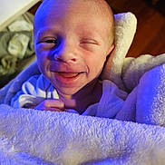 Wyatt joined the competition — help win amazing prizes! baby, infant, blanket, smile, face, winking, newborn, cozy, soft, wrapped, cute, skin, hand, expression, portrait, warm, indoor, closeup, happy, child