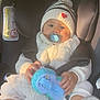 baby, child, car_seat, pacifier, hat, beanie, toy, stuffed_animal, white_clothing, shoes, socks, infant, seatbelt, car_interior, sunlight, cute, warm_clothing, portrait, indoor, closeup