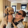 Phoenix joined the competition — help win amazing prizes! person, dog, indoor, kitchen, curly_fur, polka_dot, bow, glasses, smile, pearl_necklace, cabinet, stool, window, curtain, counter, appliance, hand, holding, playful, happy