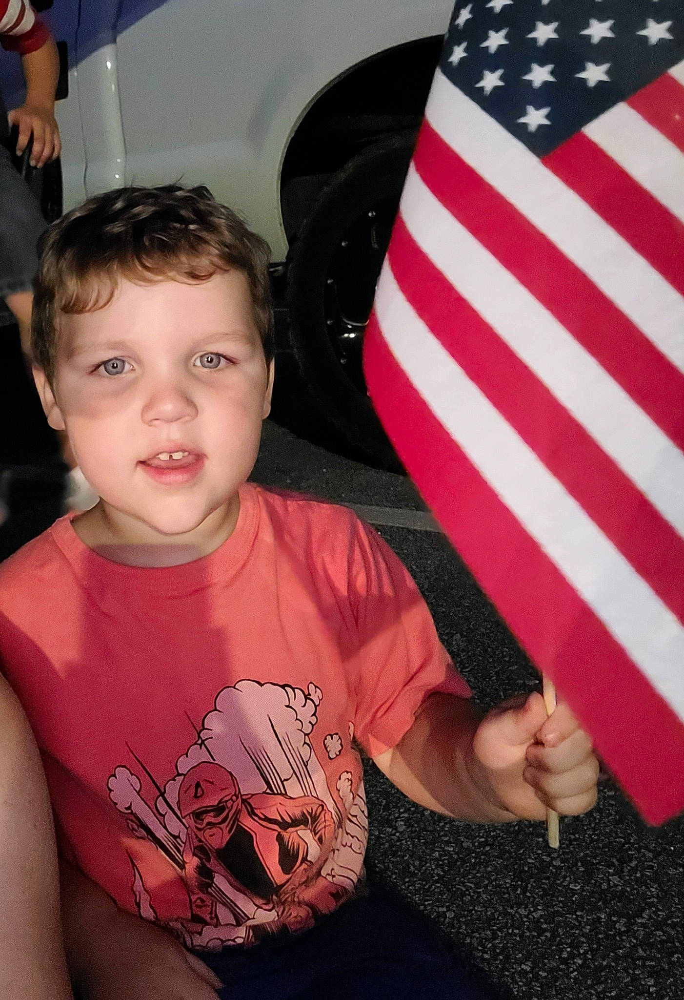 Ezra joined the competition — help win amazing prizes! automotive_design, automotive_exterior, automotive_tire, child, event, finger, flag, flag_day_usa, flag_of_the_united_states, flash_photography, fun, gesture, happy, motor_vehicle, person, sitting, sleeve, t_shirt, thumb, toddler
