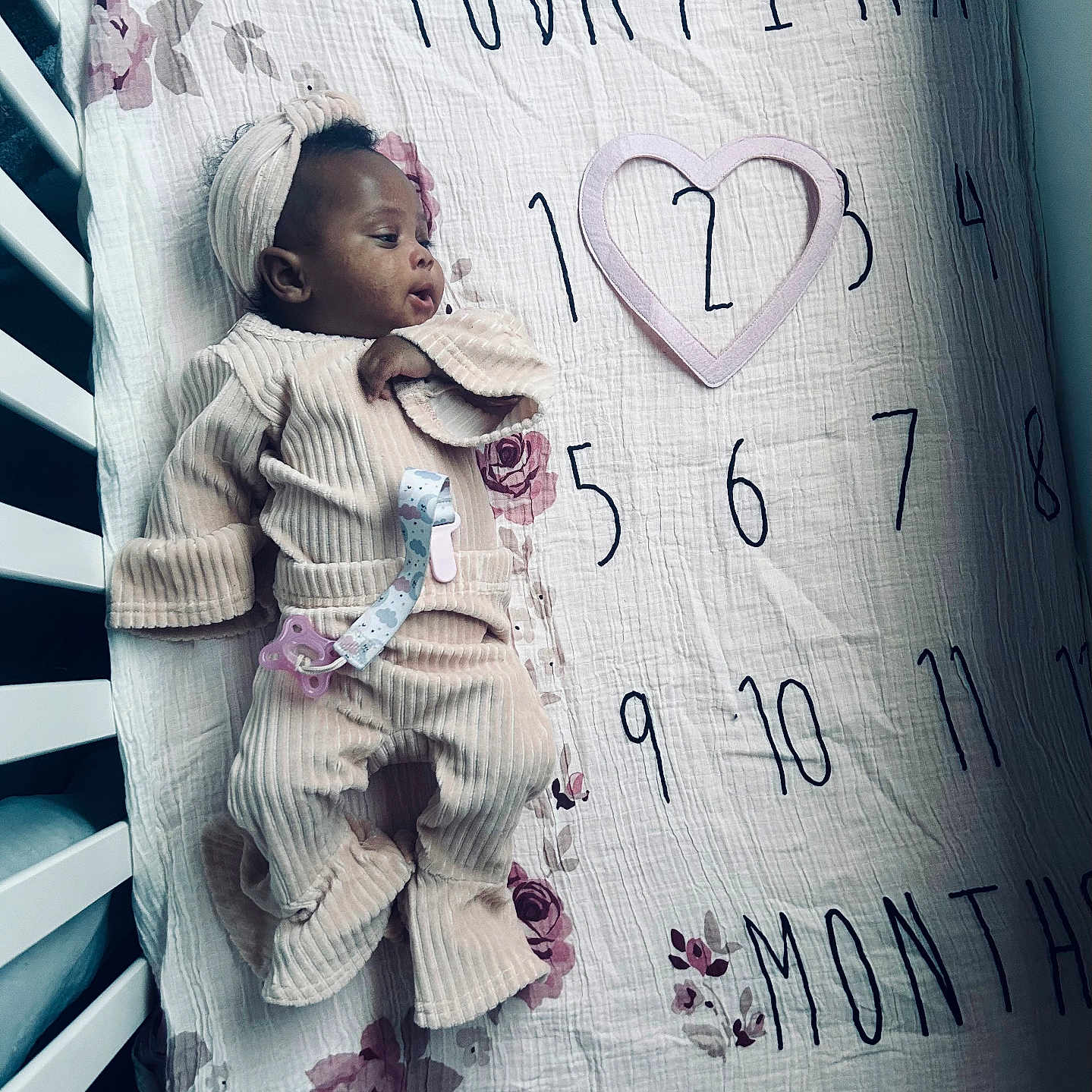 Ulanni is registered to the contest to win money with this photo: baby, blanket, clothing, crib, face, furniture, head, infantbed, person, sleeping, sleeve, symbol, text