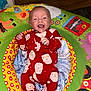 Ronniejay is registered to the contest to win money with this photo: baby, infant, smiling, red_onesie, santa_pattern, colorful_cushion, animal_print, plush, child, happy, lying_down, indoor, soft_toys, cute, festive, holiday, portrait, baby_gym, play_mat, young_child