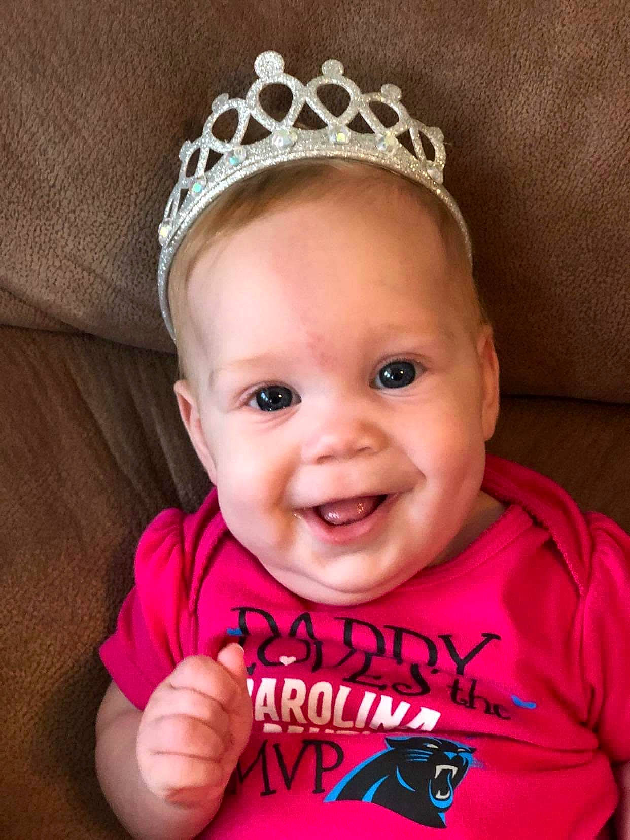 Lindsey is registered to the contest to win money with this photo: baby, baby_toddler_clothing, cheek, child, crown, face, fashion_accessory, forehead, hair_accessory, head, headband, headgear, headpiece, joy, lip, mouth, person, pink, product, smile