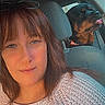 backseat, brown_hair, candid, car, companion, dog, face, glasses, happy, indoor, pet, portrait, seatbelt, selfie, sweater, tongue, travel, vehicle, window, woman