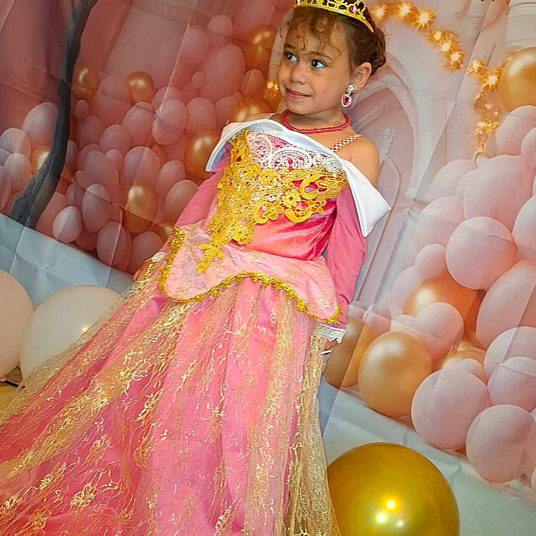 Dalyah a rejoint le concours — aidez-le/la à gagner de superbes lots ! backdrop, balloons, castle, celebration, child, costume, decor, dress, floor, girl, gold, gown, indoor, jewelry, party, pink, portrait, princess, smile, tiara