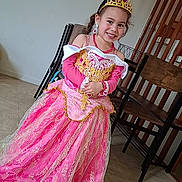 Dalyah a rejoint le concours — aidez-le/la à gagner de superbes lots ! chair, child, costume, dress, floor, girl, gold, happy, indoor, jewelry, person, pink, portrait, pose, princess, smile, tiara, wall, wood, young
