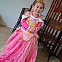chair, child, costume, dress, floor, girl, gold, happy, indoor, jewelry, person, pink, portrait, pose, princess, smile, tiara, wall, wood, young