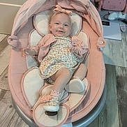 Essence is registered to the contest to win money with this photo: baby, infant, child, smile, pink, bouncer, baby_seat, headband, floral_dress, shoe, socks, wood_floor, flooring, toy, nursery, cushion, canopy, portrait, indoor, happy