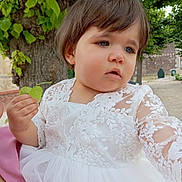 Dany is registered to the contest to win money with this photo: toddler, child, white_dress, lace, leaf, tree, outdoor, nature, greenery, portrait, young_child, curious, person, summer, daylight, expression, short_hair, cute, innocence, holding