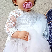 Danny a rejoint le concours — aidez-le/la à gagner de superbes lots ! toddler, child, baby, dress, white_dress, lace, pacifier, pink_pacifier, face, blue_eyes, hand, person, portrait, cute, young_child, holding, fabric, tulle, short_hair, indoor