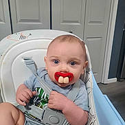 Ryker joined the competition — help win amazing prizes! baby, high_chair, pacifier, blue_eyes, gray_clothing, indoor, infant, seatbelt, face, expression, child, cute, funny, furniture, room, door, human, portrait, baby_toy, humor