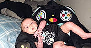 Ryker is registered to the contest to win money with this photo: baby, bed, casual, child, clothing, colorful, comfort, controller_design, cute, furniture, home, humor, indoor, infant, onesie, person, pillow, plush_chair, relaxed, soft_toys