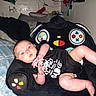 baby, bed, casual, child, clothing, colorful, comfort, controller_design, cute, furniture, home, humor, indoor, infant, onesie, person, pillow, plush_chair, relaxed, soft_toys