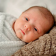 Ryker is registered to the contest to win money with this photo: baby, bedding, blanket, close_up, cozy, eyes, face, head, indoor, infant, lying_down, newborn, photography, plush, portrait, resting, skin, sleepy, soft_texture, swaddle