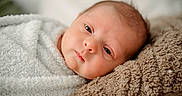 Ryker is registered to the contest to win money with this photo: baby, bedding, blanket, close_up, cozy, eyes, face, head, indoor, infant, lying_down, newborn, photography, plush, portrait, resting, skin, sleepy, soft_texture, swaddle