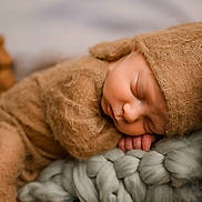 Ryker is registered to the contest to win money with this photo: newborn, baby, sleeping, brown_clothing, knit_blanket, wooden_cradle, infant, cozy, cute, soft_texture, peaceful, portrait, child, indoors, resting, hat, closeup, tiny_hands, warm_colors, snug