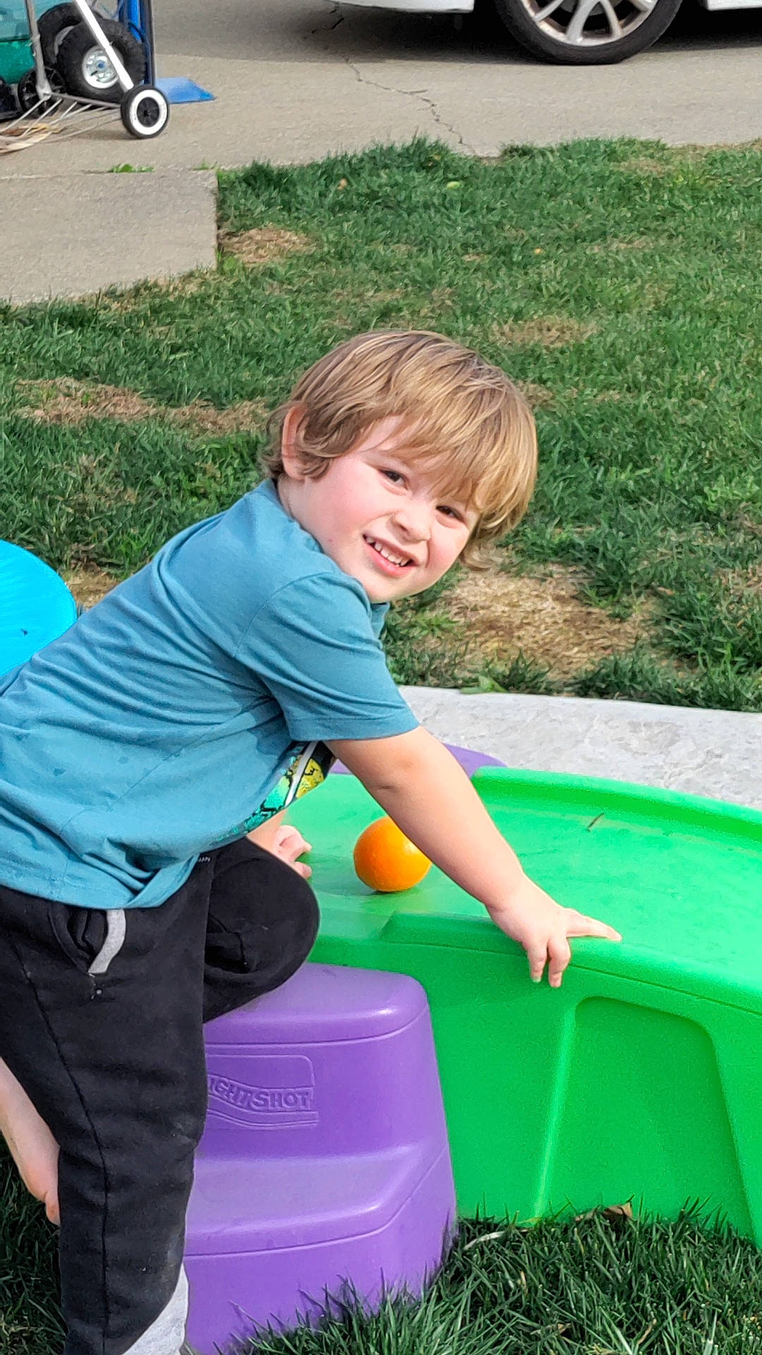 Devon is registered to the contest to win money with this photo: bicycle_wheel, child, electric_blue, fun, grass, green, happy, joy, lawn, leisure, outdoor_play_equipment, people_in_nature, person, photograph, public_space, recreation, smile, t_shirt, tire, toddler