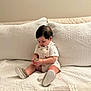 baby, child, infant, sitting, couch, quilt, white, soft, indoors, cute, hands, object, focused, clothing, shoes, hair, pillow, neutral_colors, home, portrait