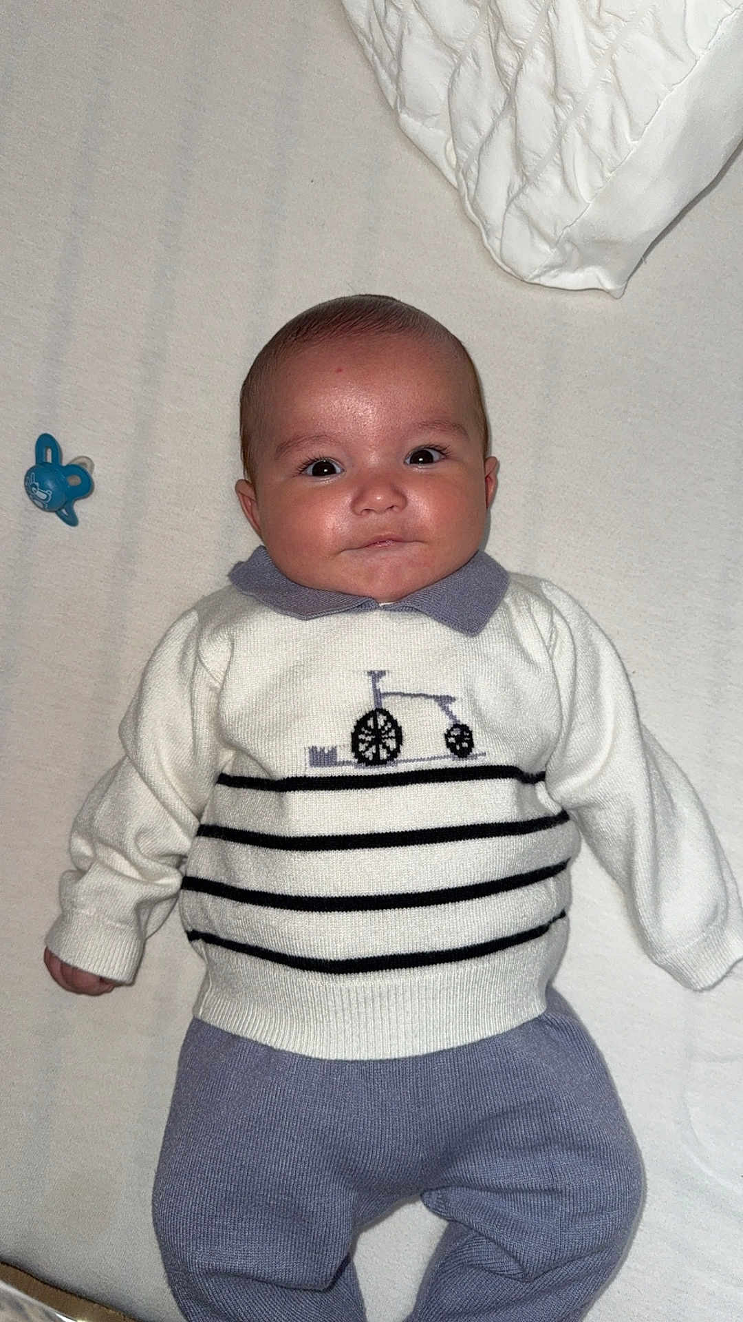 Stany participe au concours pour gagner de l'argent avec cette photo : baby, infant, child, sweater, purple_pants, blanket, pacifier, face, eyes, smile, portrait, indoor, cute, cozy, lying_down, clothing, baby_toys, person, newborn, soft