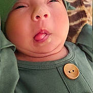 Milily is registered to the contest to win money with this photo: baby, infant, green_clothing, hat, tongue_out, funny_face, cute, child, portrait, buttoned_shirt, closeup, expression, skin, headwear, indoors, person, young_child, face, silly, squinting_eyes