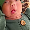 baby, infant, green_clothing, hat, tongue_out, funny_face, cute, child, portrait, buttoned_shirt, closeup, expression, skin, headwear, indoors, person, young_child, face, silly, squinting_eyes