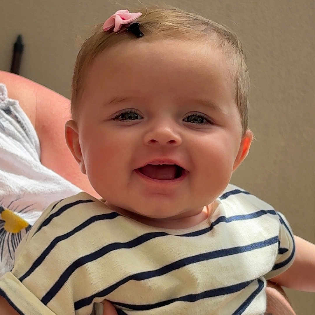 Mïa participe au concours pour gagner de l'argent avec cette photo : baby, casual_clothing, cheeks, child, closeup, cute, eyes, fingers, hair_clip, hand, happy, holding, infant, mouth, nail_polish, person, portrait, skin, smiling, striped_shirt