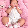 baby, child, infant, portrait, smiling, sitting, pink, blanket, teddy_bear, bow, hair_bow, white_outfit, socks, cuddly_toy, nursery, indoors, soft_blanket, baby_用品, looking_at_camera, adorable